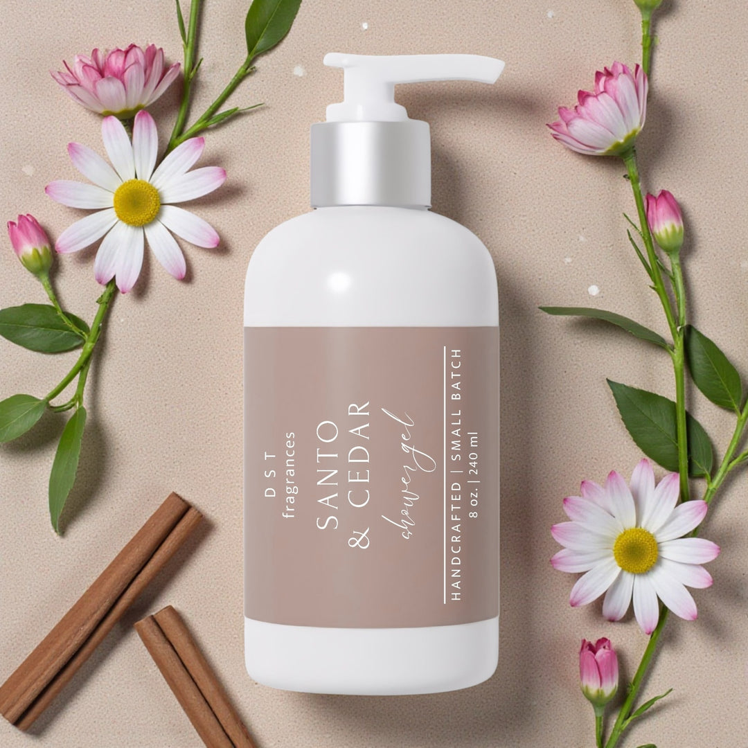 240ml bottle of Santo & Cedar scented Shower Gel by DST Fragrances lying flat on a beige background surrounded by white and pink Daisy flowers.