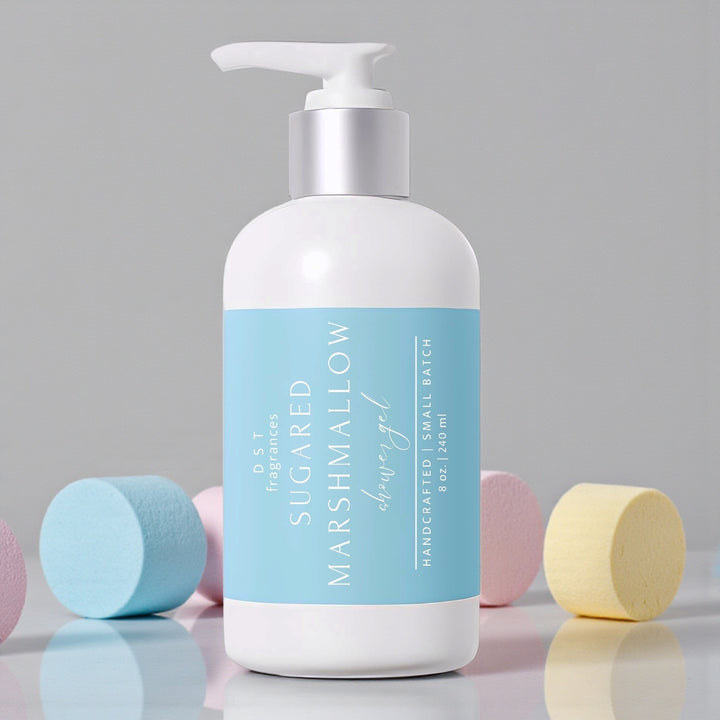 100ml bottle of Sugared Marshmallow scented Shower Gel by DST Fragrances sitting on a reflective white surface with pastel colored marshmallows and a light grey background.