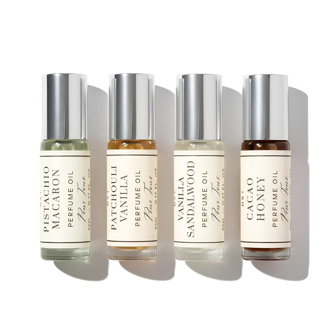 Four perfume oil bottles with labels on a white background