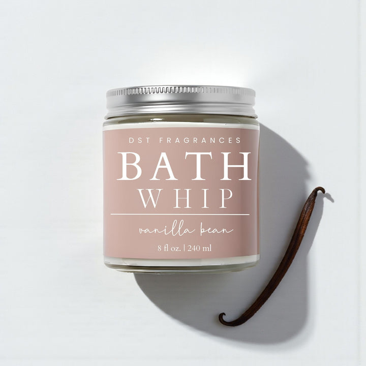 Vanilla bean bath whip container with vanilla beans on a light background