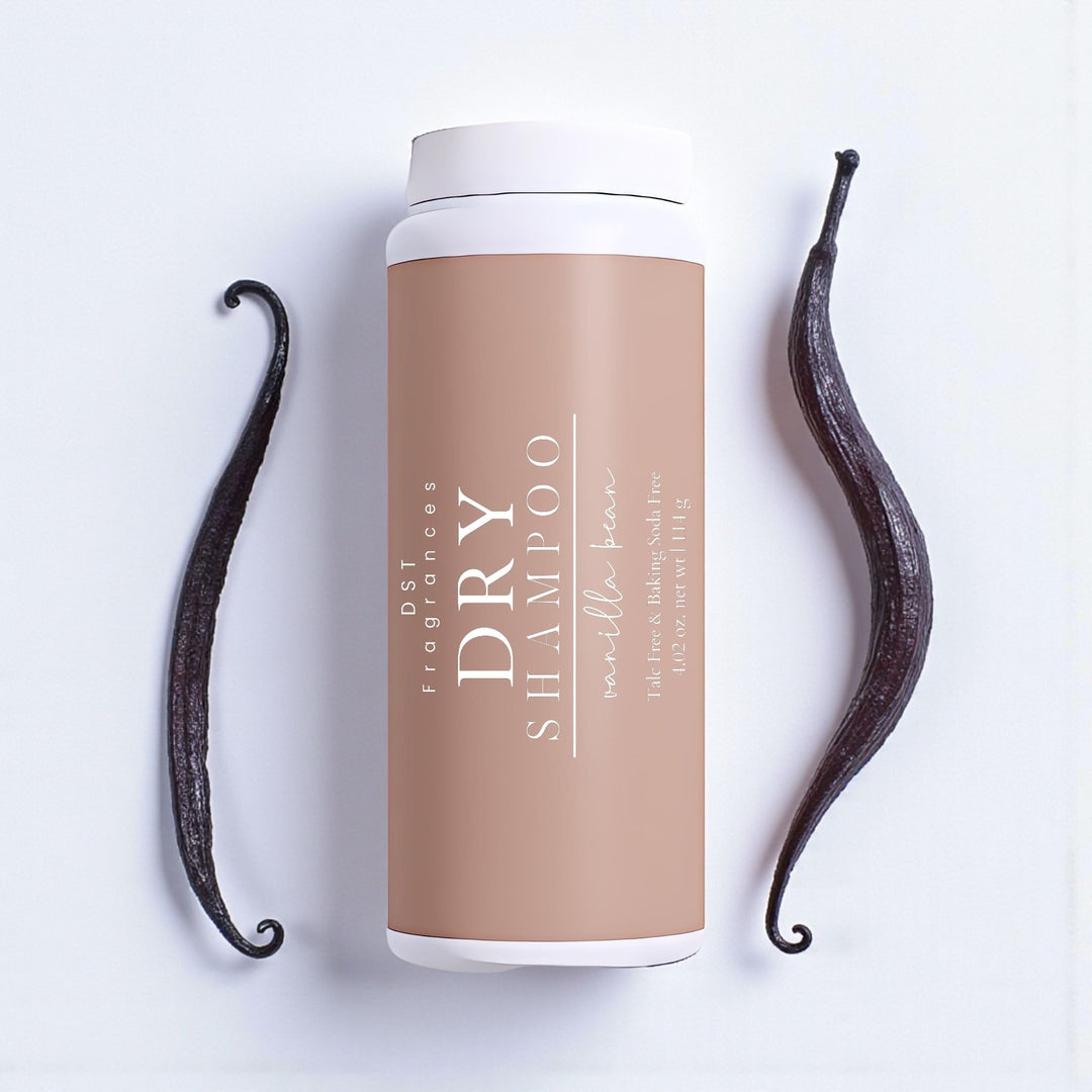 114g bottle Vanilla Bean Scented Dry Shampoo Powder by DST Fragrances against an ivory surface with 2 vanilla beans in the background.
