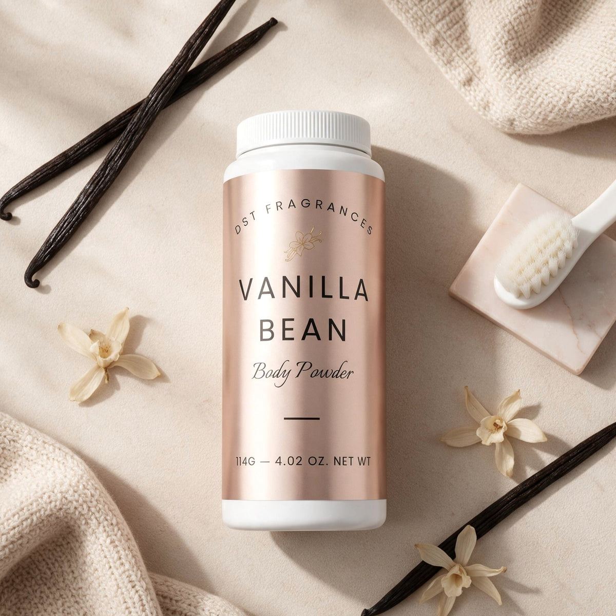 A bottle of DST Fragrances Vanilla Bean Body Powder is styled in a flat-lay arrangement on a beige fabric background with vanilla beans, dried flowers, a small brush, and a textured cloth.