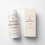 A bottle of DST Fragrances Vanilla Sandalwood Dry Shampoo next to its matching cream-colored packaging box, displayed on a clean white background.