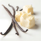Vanilla beans and chunks of creamy butter arranged on a clean white surface.