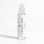 A clear glass rollerball bottle of Velvet Ash Perfume Oil by DST Fragrances, featuring a white label with black text and a small dark pink star logo, set against a clean white background.
