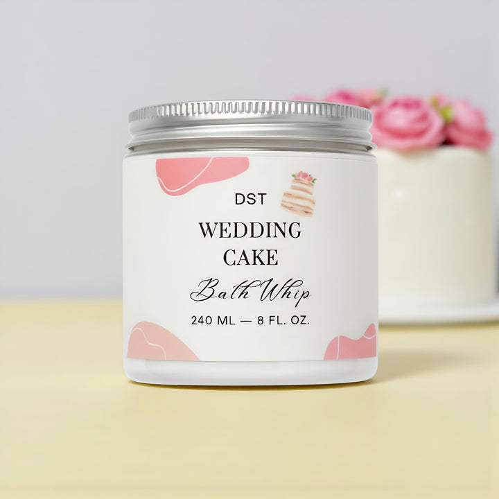 Bath whip container labeled 'Wedding Cake' by DST on a light background with a white wedding cake with pink flowers.