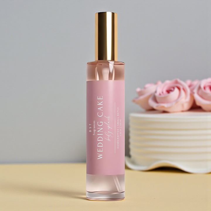 100ml bottle of Wedding Cake scented body splash by DST Fragrances sitting on a pale-yellow surface with light grey background and a white wedding cake with Pink Roses.