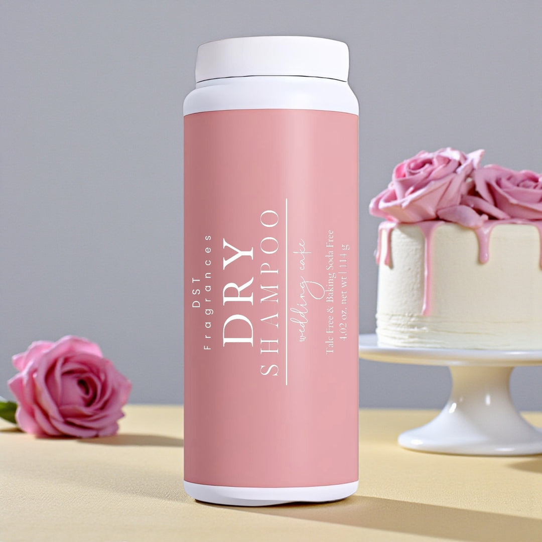 114g bottle of Wedding Cake scented dry shampoo powder by DST Fragrances sitting on a pale-yellow surface with light grey background and a white wedding cake with Pink Roses.