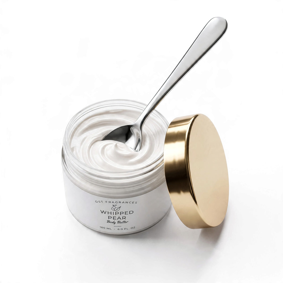 A jar of Ost Fragrances Whipped Pear Body Butter with white whipped cream inside, a gold lid resting beside it, and a silver spoon resting inside the jar, all on a clean white background.