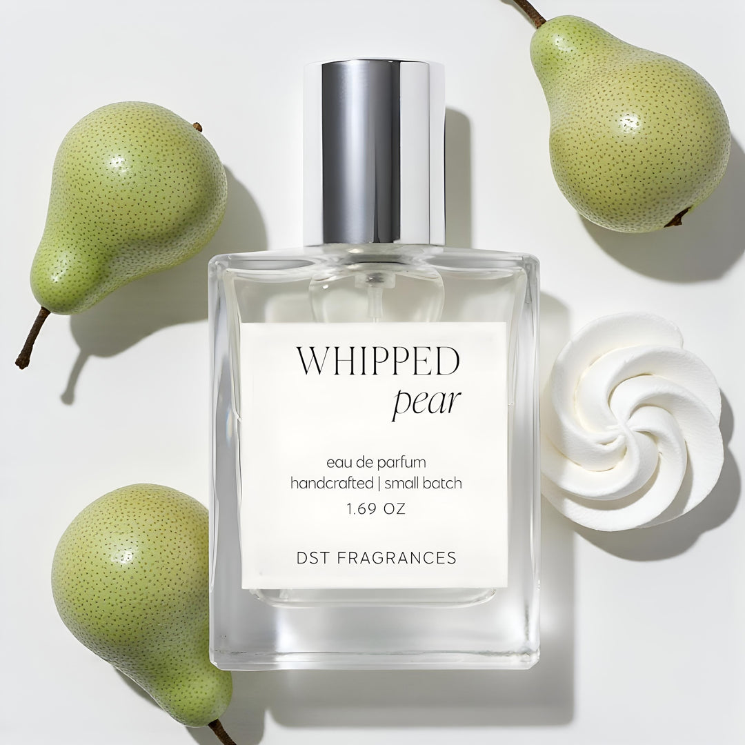 50ml bottle of Whipped Pear Eau de Parfum by DST Fragrances laying on a white surface with 3 fresh pears and a dollop of white whipped cream.