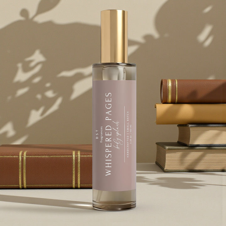100ml bottle of Whispered Pages scented body splash by DST Fragrances against an ivory background with stacks of brown leather-bound books.