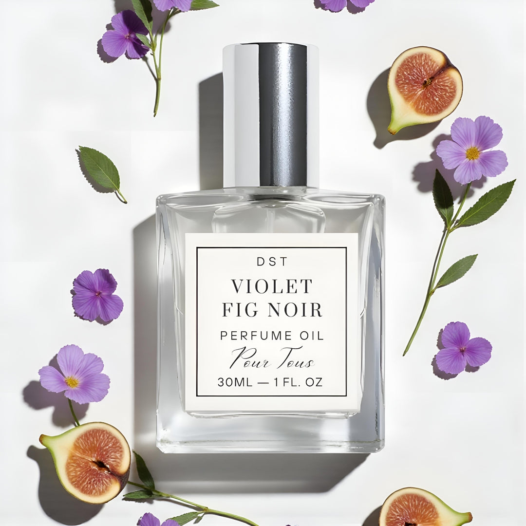 Perfume oil bottle labeled 'Violet Fig Noir' surrounded by flowers and figs on a white background